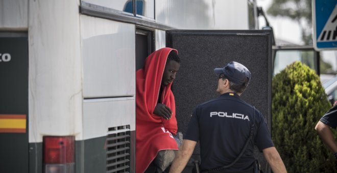 Un migrante baja del autobús de la Guardia Civil que le han trasladado del un pabellón cercano hasta el nuevo centros de atención para extranjeros habilitado en el puerto de Campamento (Cádiz).- JAIRO VARGAS