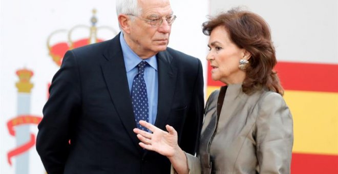 La vicepresidenta del Gobierno, Carmen Calvo y el ministro de Exteriores, Josep Borrell, conversan antes del inicio del desfile militar, uno de los actos conmemorativos del Día de la Fiesta Nacional, que presiden los Reyes junto a sus hijas, la princesa