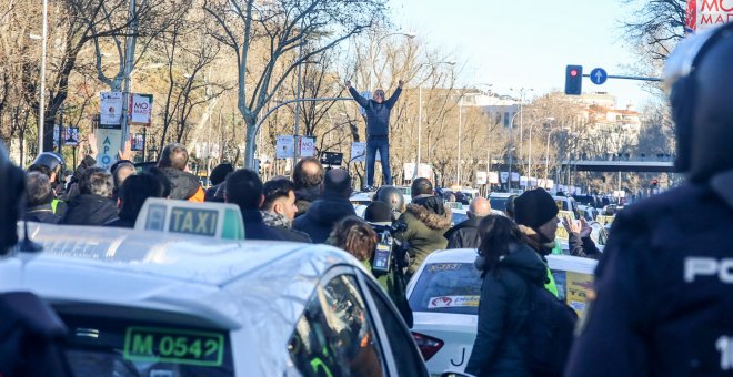 Un taxista se sube a un coche para dar una charla durante una concentración de taxistas en el Paseo de la Castellana de Madrid, donde el colectivo acampó en su séptimo día de huelga. | Ricardo Rubio / Europa Press