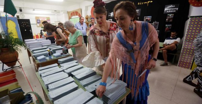 Dos mujeres vestidas de flamenca eligen sus papeletas en un colegio de Córdoba donde se está celebrado la Feria de Nuestra Señora de la Salud. EFE