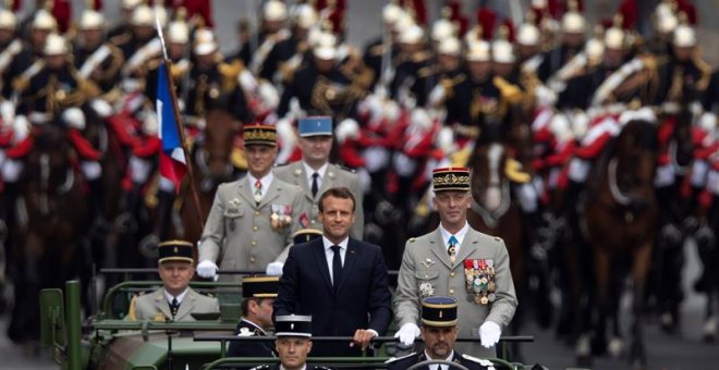 El presidente francés, Emmanuel Macron, a bordo del vehículo militar, flanqueado por la Guardia Repulblicana montada, asiste al desfile militar anual del Día de la Bastilla en la avenida de los Campos Elíseos en París.  EFE / IAN LANGSDON