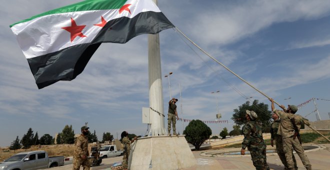 14/10/2019 - Los combatientes rebeldes sirios respaldados por Turquía alzan la bandera de la oposición siria en la ciudad fronteriza de Tel Abyad. REUTERS / Khalil Ashawi