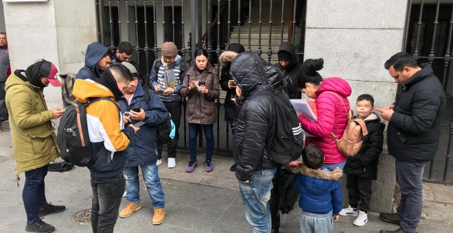 Varios solicitantes de asilo intentan reservar su cita previa de extranjería para acceder al sistema de acogida, en la puerta del Samur Social de Madrid.- RSP