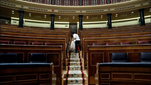 Una empleada de la Cámara limpia el hemiciclo del Congreso vacío