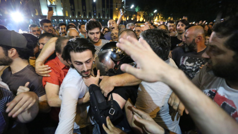 Varios manifestantes rodean a un policía antidisturbios durante una protesta convocada delante del Parlamento | EFE