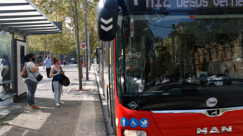 Un bus aturat a la plaça Universitat amb usuaris a la parada.