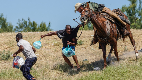 Un agente de la patrulla fronteriza de Estados Unidos a caballo intenta detener a dos migrantes haitianos en el río Grande (Texas).