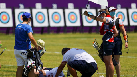 22/07/2021.- Svetlana Gomboeva (abajo) del equipo del Comité Olímpico Ruso (ROC) recibe atención al desmayarse por un golpe de calor hoy, durante la ronda de individual femenina de Tiro con arco por los Juegos Olímpicos 2020, en el campo de Yumenoshim