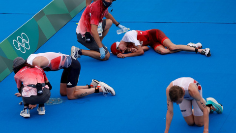 26/07/2021.- Jonathan Brownlee (i) de Gran Bretaña, Max Studer (c) de Suiza y Casper Stornes de Noruega descansan en el suelo tras cruzar la meta del triatlón masculino durante los Juegos Olímpicos 2020, este lunes en el parque marino de Odaiba en Toki