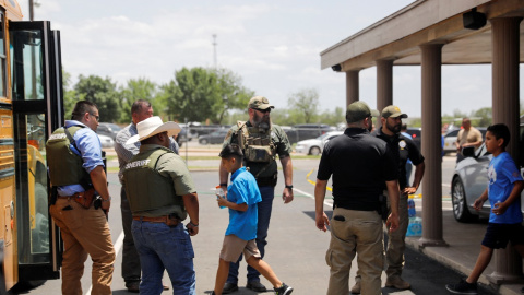 Los niños se suben a un autobús escolar mientras el personal policial vigila la escena de un presunto tiroteo cerca de la Escuela Primaria Robb en Uvalde, Texas, EE. UU. 24 de mayo de 2022.