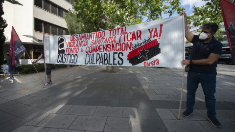 28/06/2022. Dos hombres sujetan una pancarta durante una concentración por los trabajadores fallecidos por el amianto frente a los Juzgados de Plaza de Castilla, a 14 de junio de 2021, en Madrid.