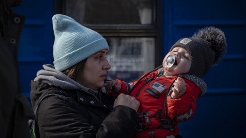 Una madre consuela a su bebé en el andén de la estación de tren de Odesa unos minutos antes de que se abran las puertas y les permitan subir