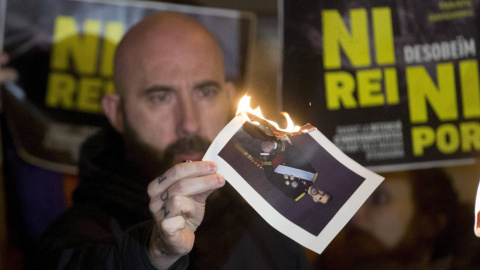 El concejal de la CUP en el Ayuntamiento de Barcelona Josep Garganté quema una foto del Rey./ EFE