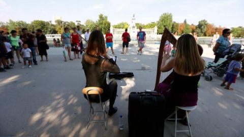 Dos jóvenes tocan junto al estanque del Retiro. EFE