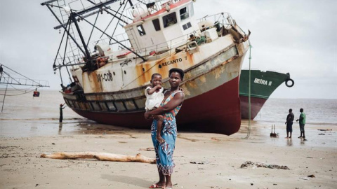 Amelia José Alberto, de 28 años, posa con Lurdes Mussa, de 5, en brazos, delante de un barco encallado en Beira. TIAGO PETINGA/EFE.