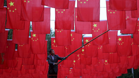 Un hombre cuelga banderas nacionales chinas para decorar un parque antes del Día Nacional de China que será el 1 de octubre, en Pekín.  REUTERS/China Daily