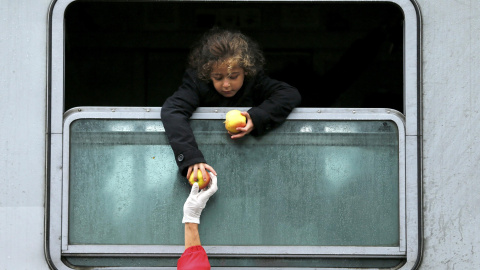 Una niña emigrante se asoma por la ventanilla del tren para coger comida en la estación de Tovarnik, en Croacia. REUTERS/Antonio Bronic