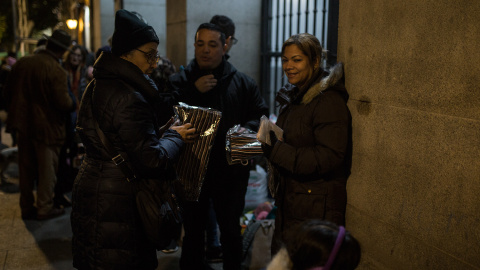 Una voluntaria reparte bufandas entre los solicitantes de asilo que esperan en las puertas del Samur Social de Madrid un plaza para pasar la noche.- JAIRO VARGAS