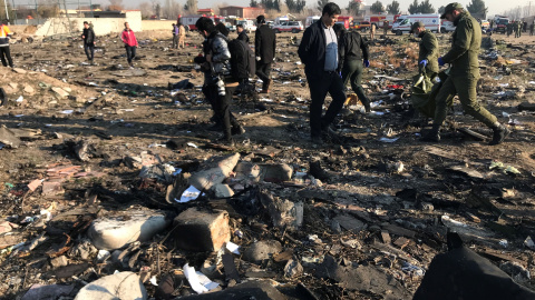 Miembros del equipo de rescate con personas revisan los escombros de un accidente aéreo perteneciente a Ukraine International Airlines después del despegue del aeropuerto iraní Imam Khomeini, en las afueras de Teherán, Irán, 8 de enero de 2