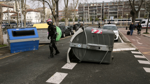 Agentes de la ertzaintza retiran una barricada colocada por grupos de estudiantes que han cortado el tráfico durante los incidentes que se han registrado hoy en el campus alavés de la Universidad del País Vasco (UPV/EHU) en Vitoria, en dond