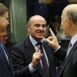 El ministro español de Economía, Luis de Guindos, conversa con el comisario europeo de Asuntos Económicos, Pierre Moscovici, en presencia del vicepresidente de la CE para el Euro y el Diálogo Social, Valdis Dombrovskis, al inicio de la reunión de los