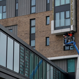 Unos trabajadores retiran el revestimiento inflamable en un bloque de viviendas en Manchester. REUTERS/Phil Noble