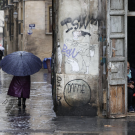 Una persona camina bajo la lluvia por las calles del centro histórico de València.