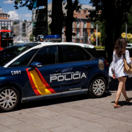 Una mujer pasa al lado de un coche de la Policía Nacional aparcado en el centro de la capital un día antes del inicio de la OTAN, a 27 de junio de 2022, en Madrid.