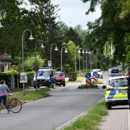 Una mujer con una bicicleta habla con un policía en una zona residencial después de que la policía de Berlín advirtiera al público que una supuesta leona andaba suelta en Stahnsdorf, cerca de Berlín , Alemania, el 20 de julio de 2023.