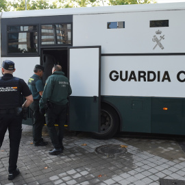 Varios agentes de la Guardia Civil y de Policía Nacional junto a un autobús de la Guardia Civil.