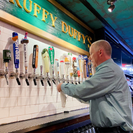 17/05/2021. Imagen de archivo del dueño del bar Pat Hughes limpiando los grifos de cerveza, en Nueva York. - REUTERS