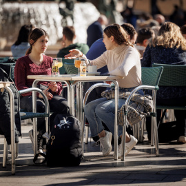 Varias personas disfrutan de un soleado día de invierno en una terraza en la ciudad de València.