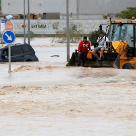 Dos ocupantes de un vehículo son rescatados con una pala mecánica, mientras la carretera permanece inundada por el efecto de las riadas, este viernes, en la ciudad alicantina de Orihuela, que se encuentra incomunicada, a causa del desbordamiento del rí