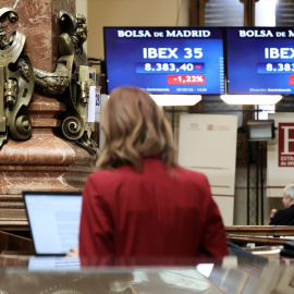 Una mujer consulta los valores del Ibex 35 en los paneles del Palacio de la Bolsa de Madrid