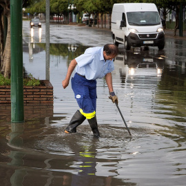 Un trabajador achicando el agua en mitad de la acera en Málaga./EFE