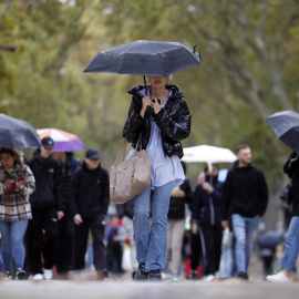 Una mujer se protege de la lluvia en las Ramblas de Barcelona, en una imagen de archivo.