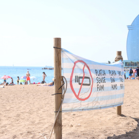 Pancarta que recorda la prohibició de fumar amb l'Hotel W Barcelona de fons.