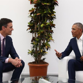 El presidente del Gobierno español, Pedro Sánchez, conversa con el expresidente de Estados Unidos, Barack Obama./EFE