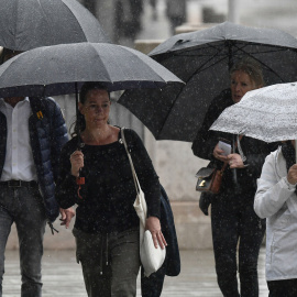 Varias personas se protegen de la lluvia en Palma de Mallorca (Illes Balears), en una imagen de archivo.