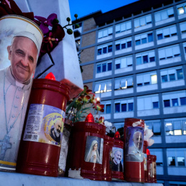 Una vela con la imagen del Papa Francisco, al pie de la estatua de San Juan Pablo II en las afueras del Hospital Universitario Gemelli, en Roma, donde el Papa Francisco se encuentra hospitalizado.