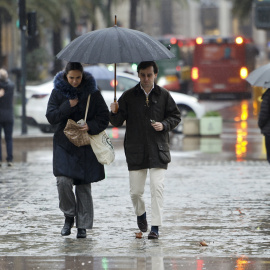 Varias personas se protegen de la lluvia en València, a 5 de marzo de 2025.