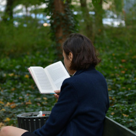 Una mujer leyendo un libro en un parque.