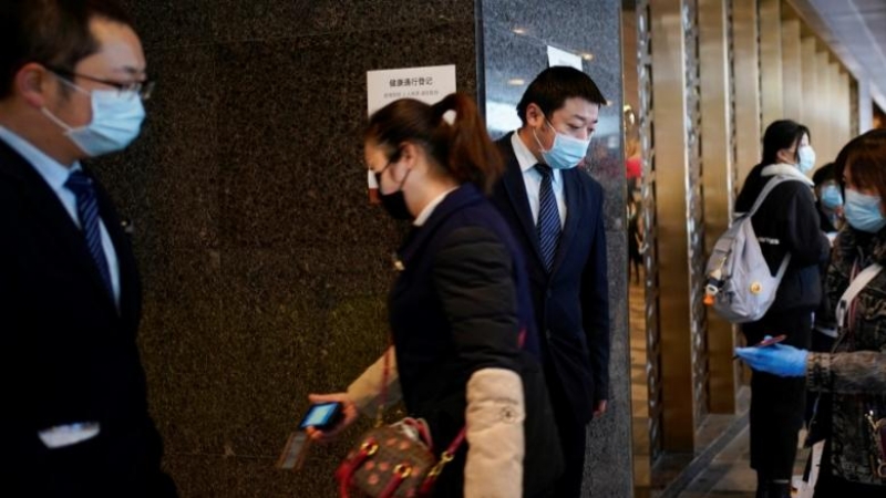 El personal de administración verifica los códigos QR en los teléfonos móviles de las personas que ingresan a un centro comercial en su entrada en Wuhan, provincia de Hubei, el epicentro del brote de la enfermedad del coronavirus de China (COVID-19), 30 d