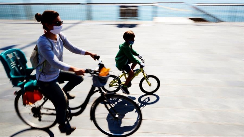 Madre e hijo en bicicleta disfrutan del día soleado en el paseo marítimo de Barcelona, este domingo en el que los menores de catorce años podrán salir a la calle por primera vez, cuando se cumple el cuadragésimo cuarto día de aislamiento social tras la a