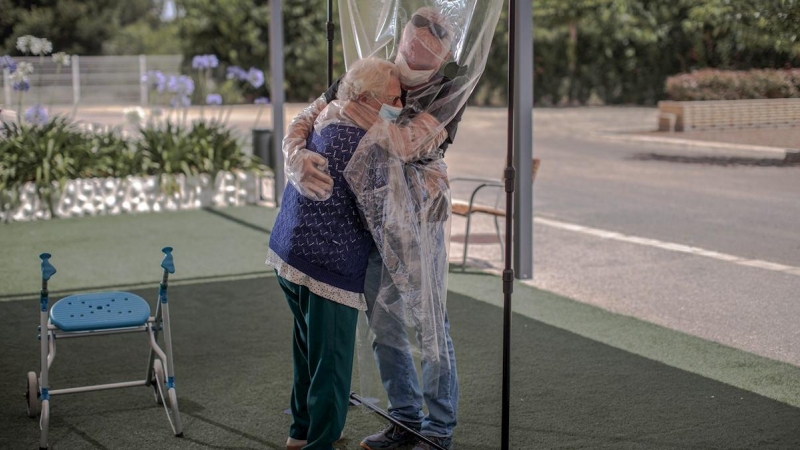 17/06/2020.- Una residente en una residencia de València abraza a su hijo a través de un plástico. / EFE - BIEL ALIÑO