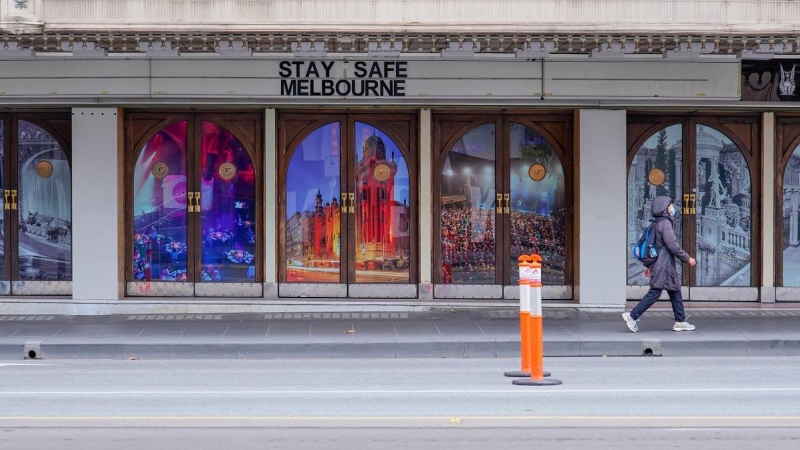 Una mujer pasa junto a un letrero de 'Stay Safe Melbourne' en una calle del centro de la ciudad.
