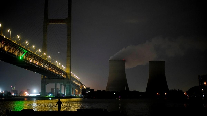 Un hombre camina a la orilla del río Huangpu cerca de una central eléctrica de carbón en Shanghai, China.