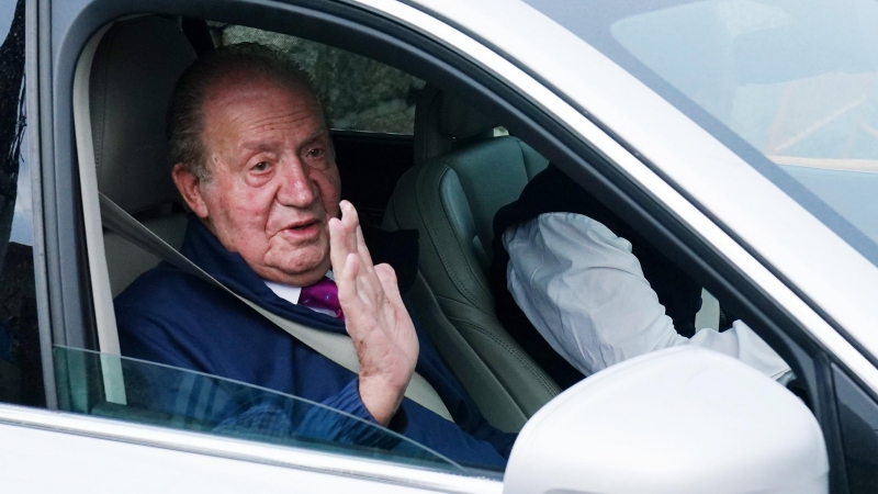 El rey emérito Juan Carlos I saluda desde un vehículo a su salida de la casa de Sanxenxo camino de Madrid, a 23 de mayo de 2022, en Sanxenxo.