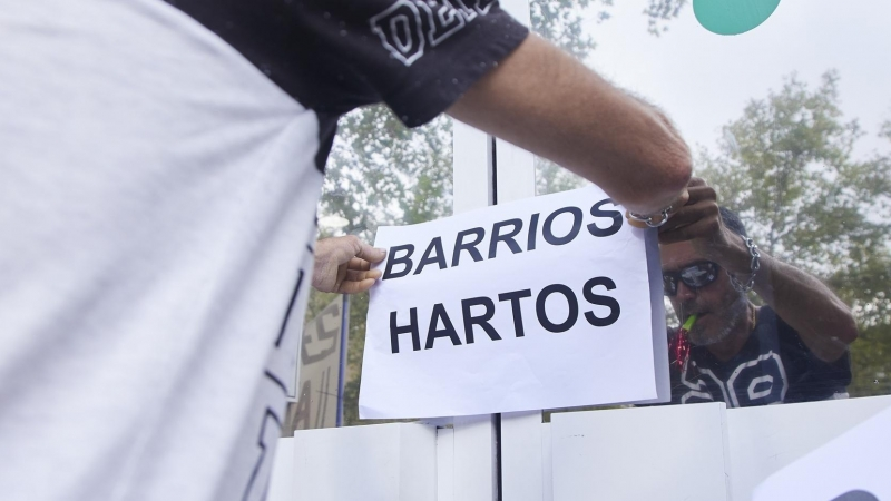 Un vecino coloca un cartel en la puerta de una oficina durante una protesta del colectivo Barrios Hartos. Imagen de archivo.