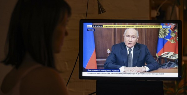 Una mujer mira un discurso televisado del presidente ruso Vladimir Putin, en Moscú, Rusia.